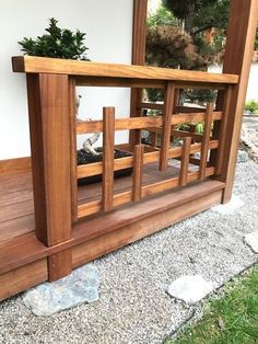 a wooden deck with plants on it and some rocks in the ground next to it