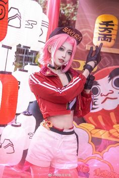 a woman with pink hair and white shorts posing for a photo in front of a wall