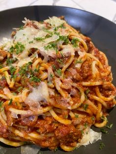 pasta with meat, cheese and parmesan in a black bowl on a table