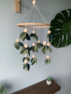 a green plant is hanging from a wooden beam in front of a gray wall and a white potted plant