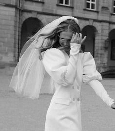 black and white photograph of a woman in a wedding dress holding her hands up to her face