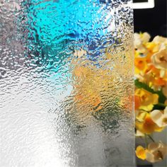 flowers are sitting in front of a frosted glass window with water droplets on it