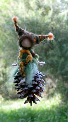 a needled doll hanging from a pine cone