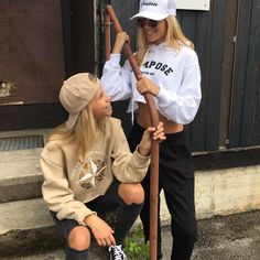 two young women sitting on the steps with baseball bats in their hands and one holding an umbrella