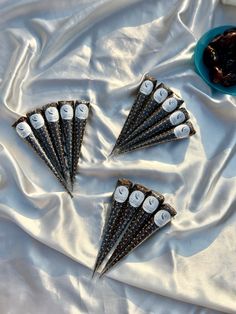 six cones with numbers on them sitting on a white sheet next to a bowl of fruit