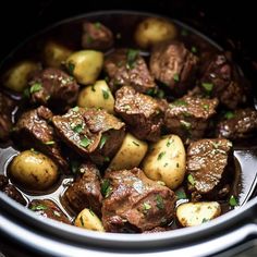 beef and potatoes are cooked in the crockpot with parsley on top, ready to be eaten