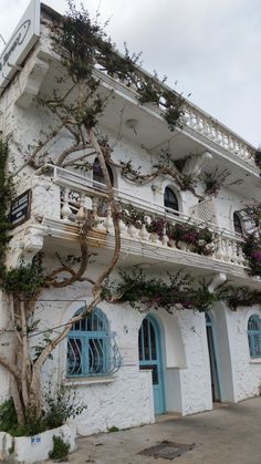 a white building with blue shutters and flowers on the balconies