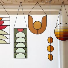 several stained glass hanging from the ceiling in front of a white wall with wood slats