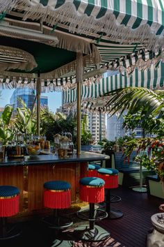 an outdoor bar with colorful stools and umbrellas over it's bar area