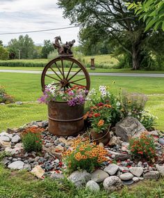 a garden with rocks, flowers and a wheel in the middle on top of it