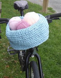 two balls of yarn are in a basket on the back of a bicycle