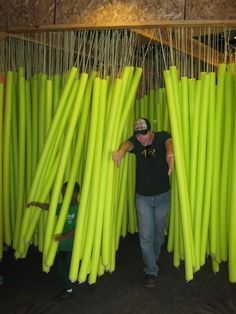 a man is standing in front of large green sticks that are hanging from the ceiling