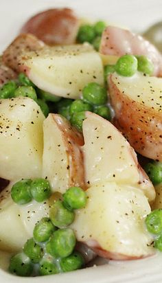 a white plate topped with potatoes and peas