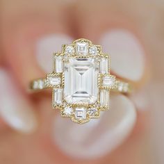 a woman's hand holding a ring with an emerald and white diamond in it