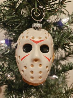 a christmas ornament with a mask hanging from it's side on a tree