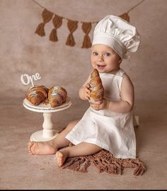 a baby sitting on the floor with some croissants in front of her