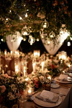 a long table with candles and flowers on it is set up for a formal dinner