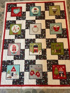 a quilted table topper on the floor with christmas decorations and houses in it