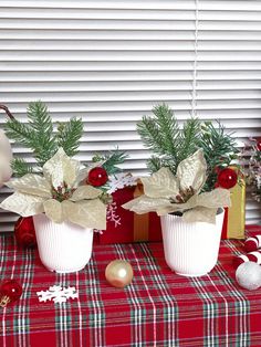 two white vases with christmas decorations on a table