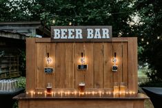 an outdoor bar with lights on it and beer glasses in front of the sign that says beer bar