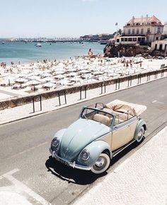 an old car is parked on the side of the road next to the ocean and beach