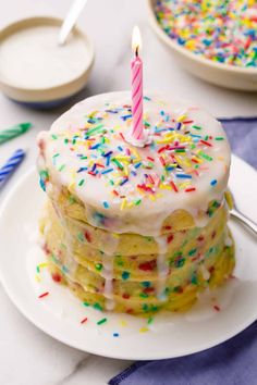 a birthday cake with white frosting and colorful sprinkles on a plate