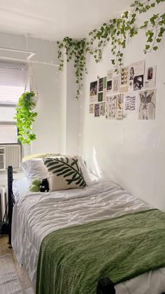 a bedroom with white walls and green plants hanging on the wall above the bedspread