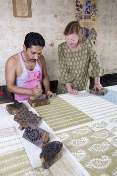 a man and woman are working on some art work with wood blocks in front of them