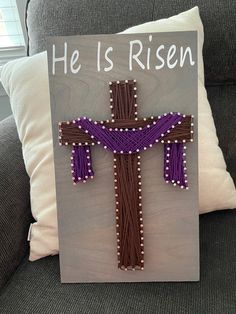 a sign with a cross on it that says he is risen in purple and brown beads