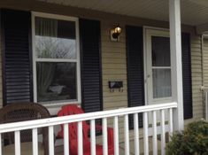 the front porch of a house with two chairs on it