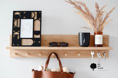 a wooden shelf holding a purse, sunglasses and a photo frame on it with a plant in the corner