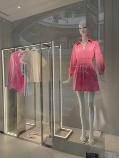 two mannequins dressed in pink and white clothing on display at a store