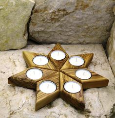 four tealight candles are arranged in the shape of a star on top of a rock