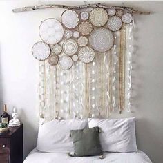 a white bed topped with lots of pillows next to a wooden headboard covered in circles