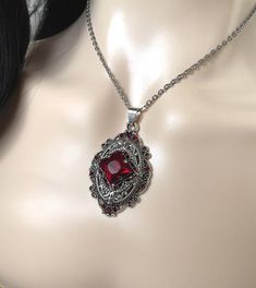 This richly detailed antiqued silver plated filigree pendant, is adorned with dazzling DARK RUBY RED glass rhinestones that perfectly accentuate a larger jewel in the center. Pendant measures 2 1/4" tall (including the bail) and 1 1/4" wide. It is worn on a cable chain in your choice of length and fastens with a lobster clasp.Listing is for necklace ONLY. Matching earrings are listed in our store.This is available in a variety of stone colors in our store, along with matching earrings. If you do Red Metal Filigree Jewelry, Red Locket Necklace For Wedding, Red Victorian Engraved Necklace, Victorian Red Engraved Necklace, 1920 Style, Red Pendant Necklace, Silver Jewlery, Victorian Necklace, Carnelian Necklace