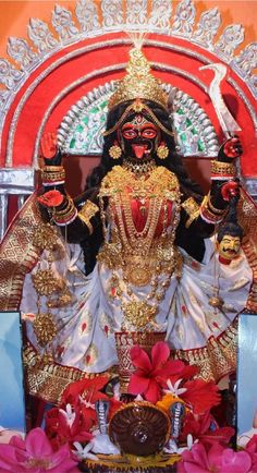 an idol is displayed in front of a red and white backdrop with flowers on the floor