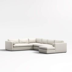 a white sectional couch sitting on top of a white floor next to a chair and ottoman