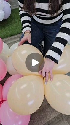 a woman is holding balloons in front of her face and touching them with her hands