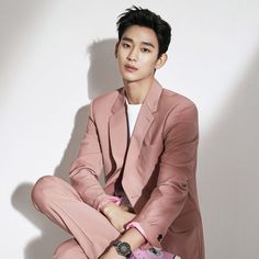 a man in a pink suit sitting on the ground with his legs crossed and hands folded