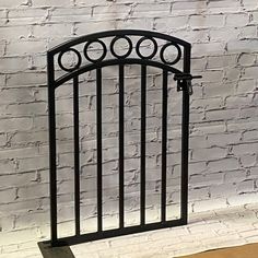 an iron gate stands against a white brick wall, with circles on the top and bottom