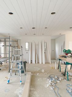 an unfinished room with ladders and paint on the floor in preparation for remodeling