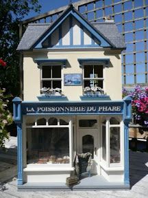 a doll house sitting on top of a wooden table in front of a building with windows