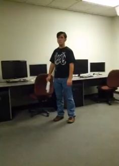 a man standing in an office with two monitors