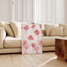 a living room with a couch, coffee table and painting on the floor in front of it