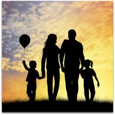 a family silhouetted against the sunset holding hands and flying a balloon in the sky