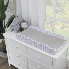 a white dresser with a baby's crib on it and a stuffed animal next to it