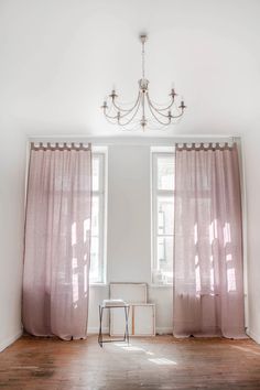 an empty room with two windows and a chandelier