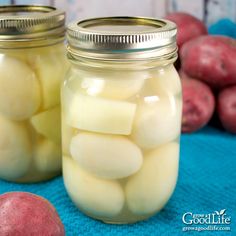 two mason jars filled with pickled potatoes on a blue cloth next to red potatoes