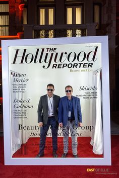 two men standing next to each other in front of a hollywood reporter poster on the red carpet