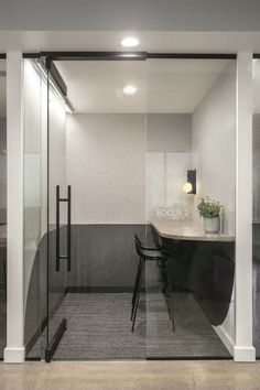 an office with glass walls and desks in the corner, next to a black chair